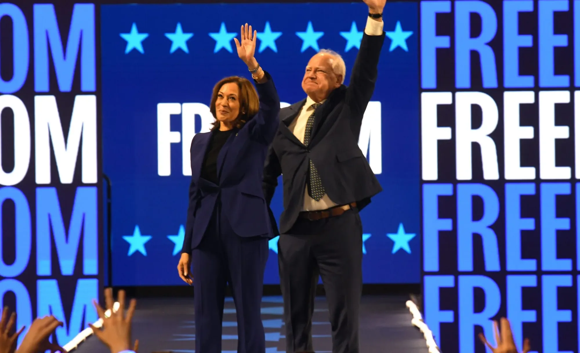 Kamala Harris and Tim Walz waiving to the crowd on stage